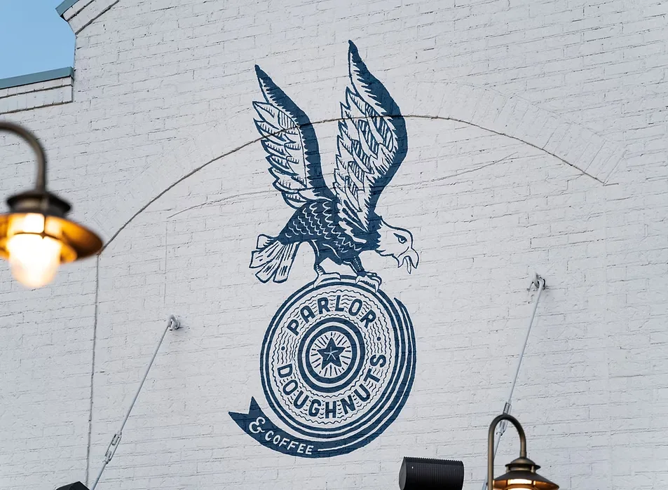 Parlor eagle-and-seal mural painted on a white brick wall