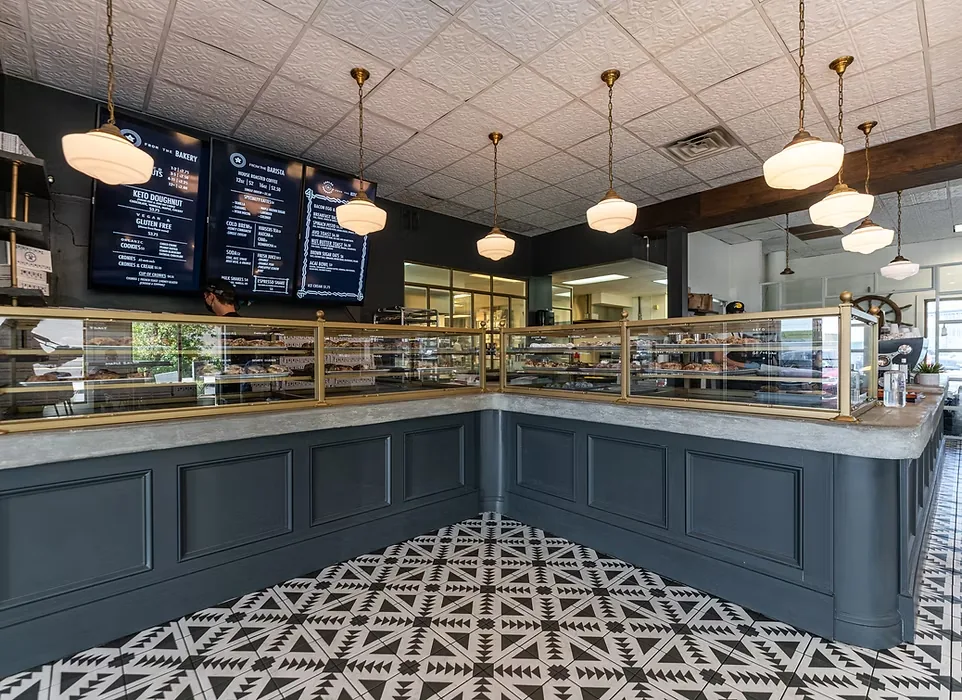 Parlor shop interior with pendant lights, a navy counter and a patterned tile floor